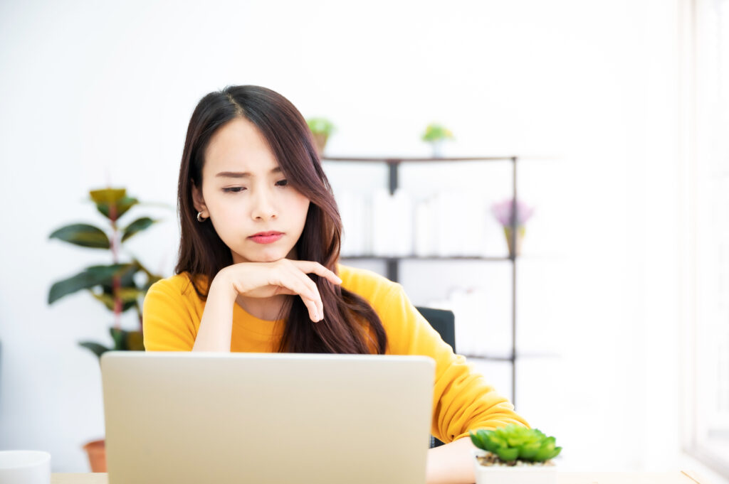Asian young woman seriously working on computer laptop in house She thinking find solution problem of work - 総合経営コンサルタント いなかん